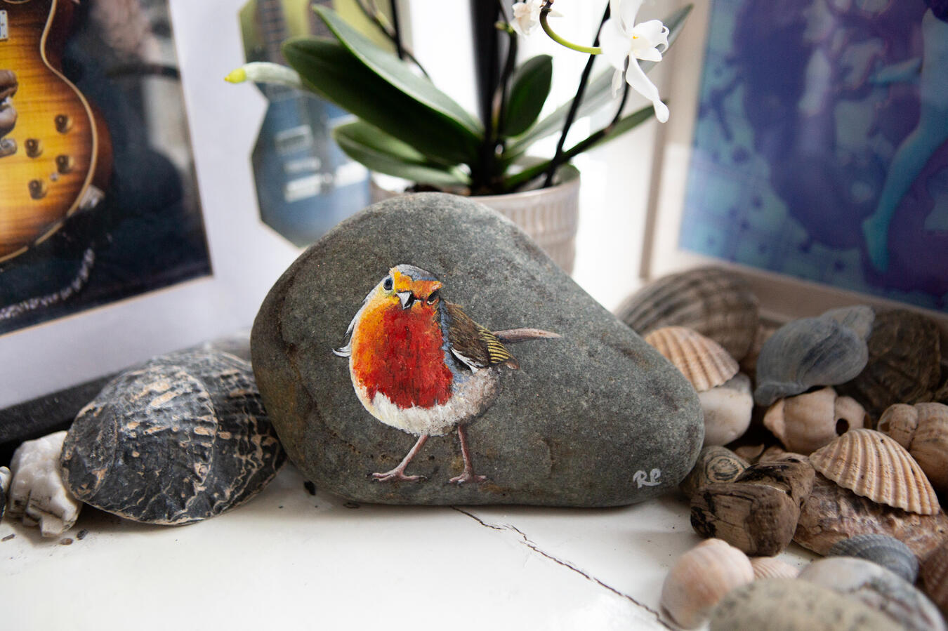 A robin with it's head cocked to one side painted on a smooth rounded piece of granite